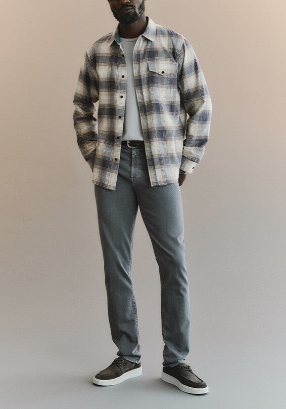 Person wearing a plaid shirt, gray pants, and black shoes on a plain background