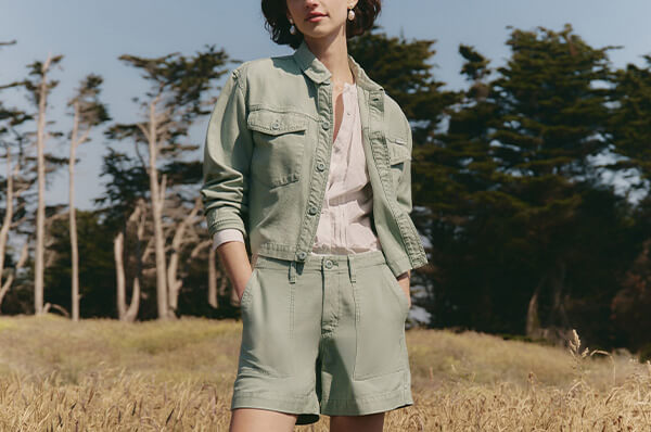 Person wearing a green outfit standing in a field with trees in the background