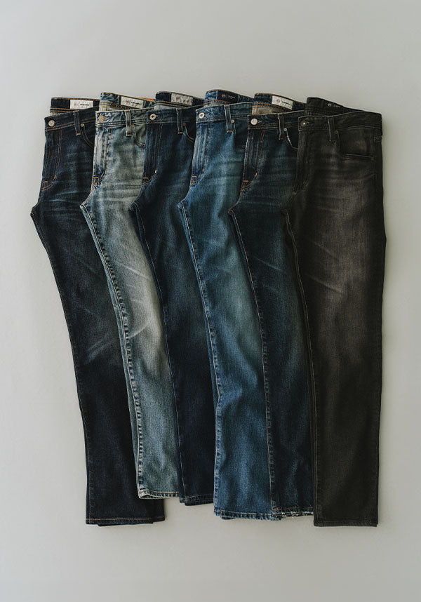 Five pairs of jeans in different denim washes, arranged vertically in a fan shape on a light gray background.