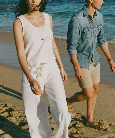 Two people walking on a beach with ocean waves in the background