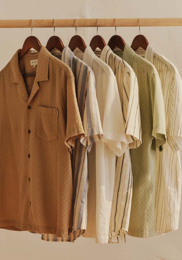 Collection of shirts hanging on a rack with a neutral background